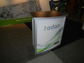 RENTAL:  RE-2028 Includes Back Wall Structure with (2) Flat Canopies, SEG Tension Fabric Graphic, (5) Halogen Arm Lights, and (3) RE-1228 Small Curved Counters with Interior Shelves and Locking Doors -- Image 3