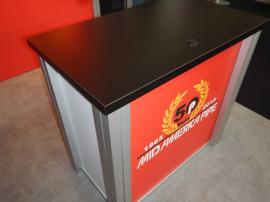 RENTAL: RE-1212 Design Includes Flat Canopy, Large Monitor Mount, RE-1202 Counter with Locking Door and Interior Shelf, RE-170 Literature Shelves, Arm Lights, Tension Fabric Graphics, and Sintra Infill Graphic -- Image 2