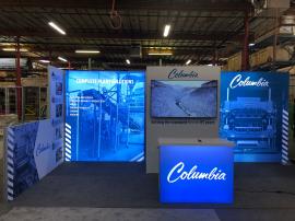 RENTAL: Modified RE-2064 Inline Design with Gravitee Panel System Storage Closet with Locking Door, Monitor Mount, 65&rdquo; Monitor, (2) Lightboxes, RE-1576 White Laminated Reception Counter, Short Return Wall, and SEG Fabric Graphics