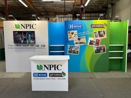 RENTAL: Inline Design with Gravitee Panel System Backwall, (6) 28" Wide x 10" Deep White Laminated Shelves, Large Monitor Mount, 43" Monitor, (6) LED Arm Lights, RE-1558 Gravitee Reception Counter, SEG Fabric Graphics -- View 2