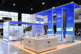 RENTAL: Custom Island Rental Design with Gravitee Storage Tower @ 96" Wide x 42" Deep x 190" High, (1) Double-Sided Lightbox @ 9 ft. Wide x 9 ft. High, (3) Double-Sided Lightbox Kiosks, (6) RE-1594 Workstation Counters with Recessed RGB Accent Lighting, (