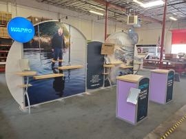 Modified VK-2965 Modular Exhibit with Tension Fabric Graphics, Backlit Circle Signage, (3) Workstations, (5) Literature Trays, (2) MOD-1297 Pedestal Counters with Locking Storage, Monitor Mount, and Large Shelves