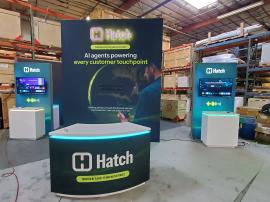 RENTAL: Custom Island Design with Modified RE-1709 Gravitee Storage Tower at 118" Wide x 42" Deep x 142.5" High, with Locking Door, (2) 3D Halo Lit Logo Graphics, Large Monitor Mount, 85" Monitor, (2) 48" Wide x 96" High Double-Sided Lightbox Kiosks, (4)