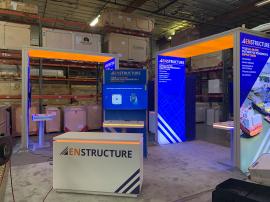 RENTAL: Modified RE-9176 Island Design with (4) 4' Wide x 10' High Double-Sided Lightboxes, (2) 10' Long x 4' Wide Single-Sided Ceiling Lightboxes, (1) 46" Wide x 95" High Double-Sided Gravitee Kiosk, (4) Large Monitor Mounts, (4) 55" Monitors, Gravitee S