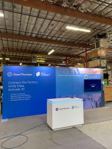 RENTAL: RE-2167 Inline Design with 232" Wide x 96" High Backwall, (4) LED Arm Lights, Large Monitor Mount, 55" Monitor, RE-1576 Reception Counter with Recessed RGB Accent Lighting, SEG Fabric Graphic, and Direct Print Vinyl Graphic