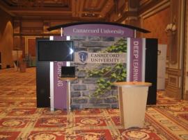 RENTAL Exhibit -- Pavilion with multiple 10’ exhibits, arch-shape canopies with black covers, Sintra accent wings, tapered counter workstations, 16’ high exhibits, kiosks -- Image 1