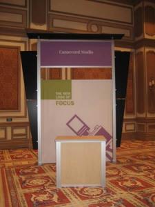 RENTAL Exhibit -- Pavilion with multiple 10’ exhibits, arch-shape canopies with black covers, Sintra accent wings, tapered counter workstations, 16’ high exhibits, kiosks -- Image 5